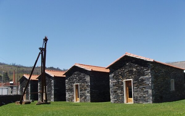 Casas de pedra com telhados de barro vermelho, em linha, com estrutura de madeira alta ao lado